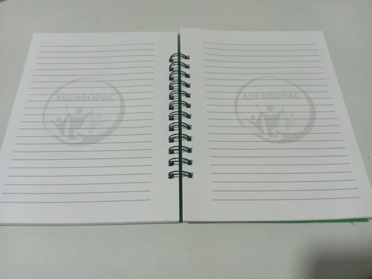 Cuaderno abierto con hojas rayadas y el logo de ASEABOPAC en marca de agua gris al centro
