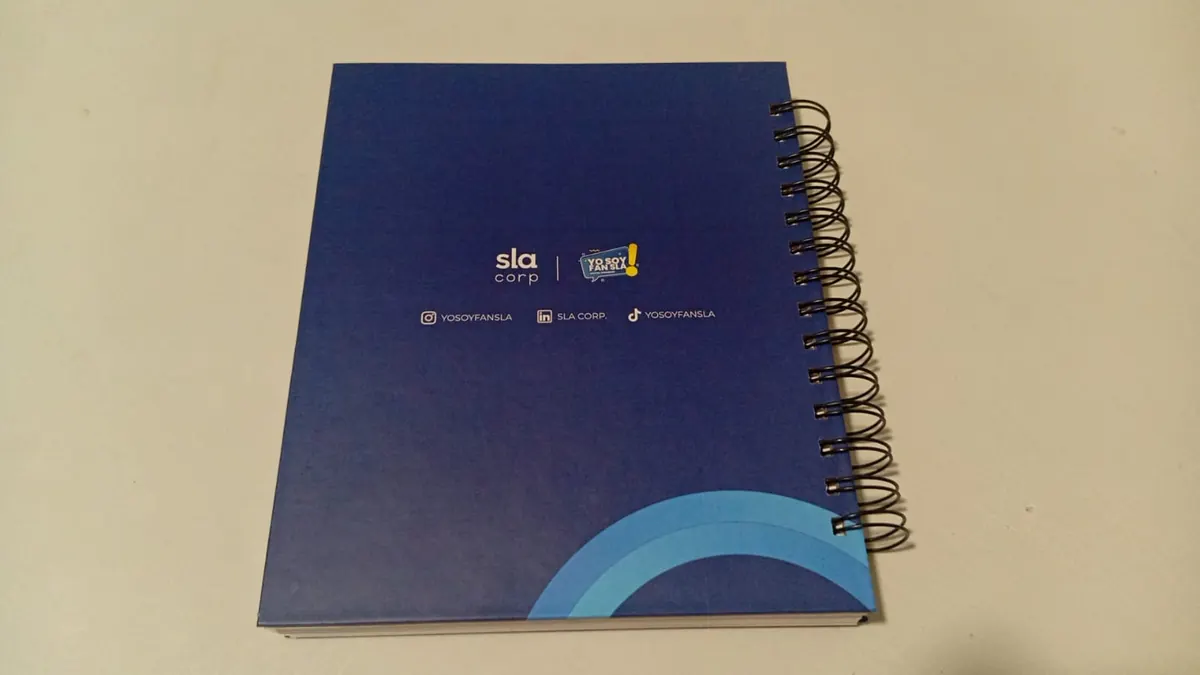 Contraportada azul de cuaderno corporativo con logo y redes sociales, laminado mate y wire-o metálico