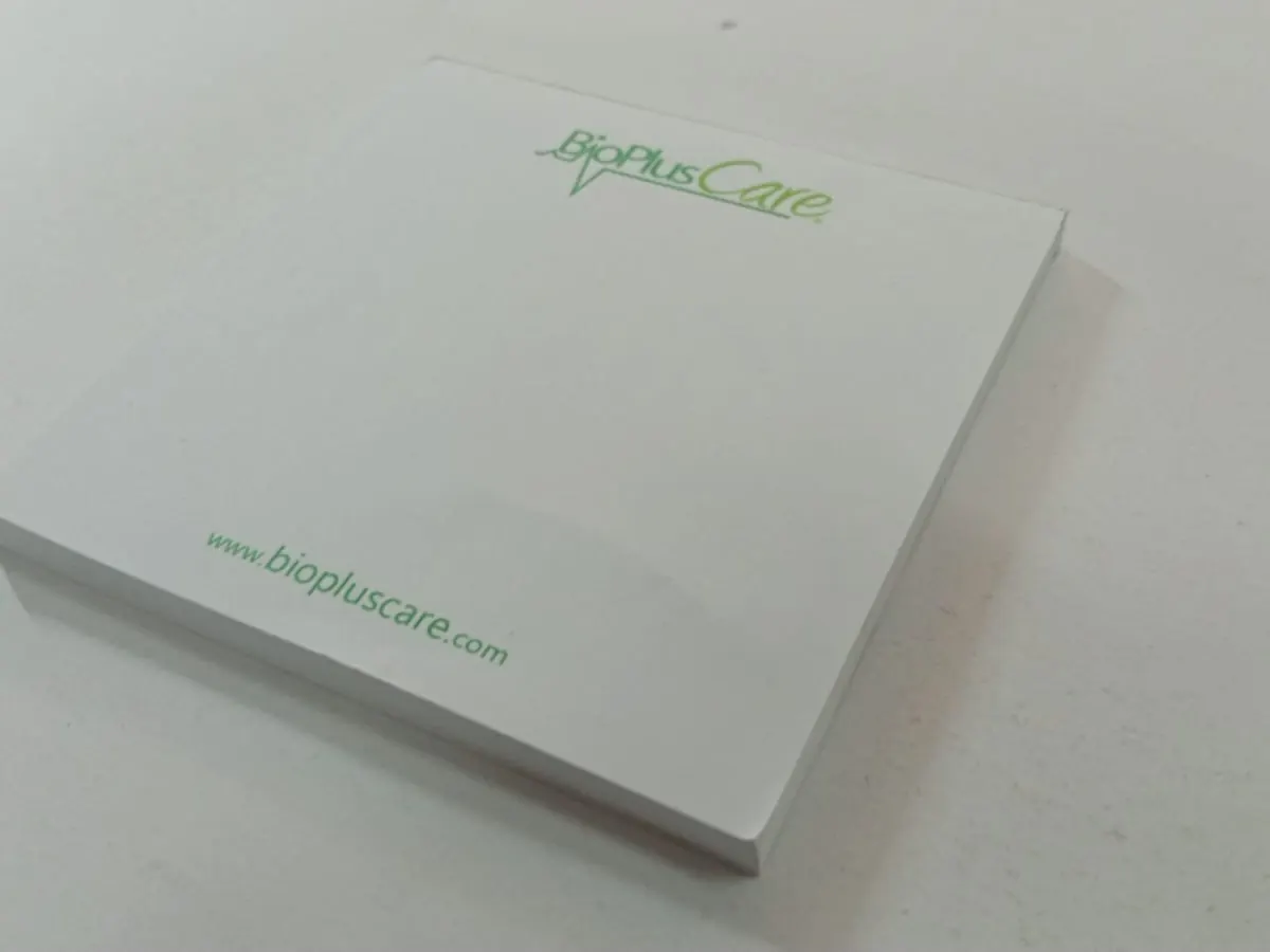Bloc de notas blanco con logotipo y sitio web impresos en verde