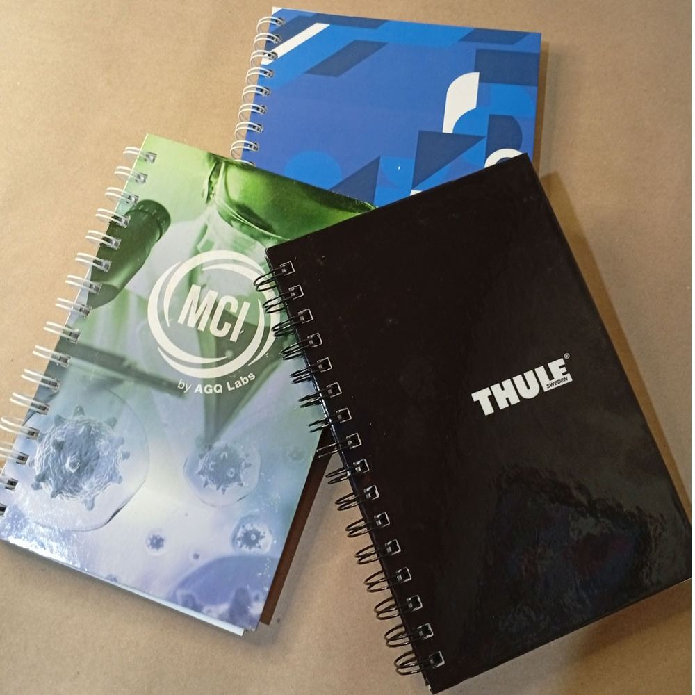 Tres cuadernos corporativos de tapa dura con encuadernación doble O, impresos para distintas empresas