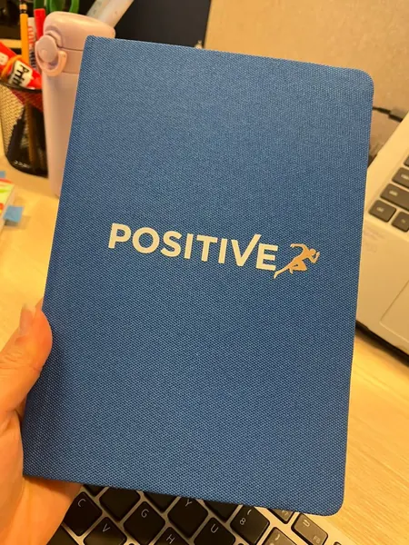 Libreta de tela azul con logotipo en blanco y dorado