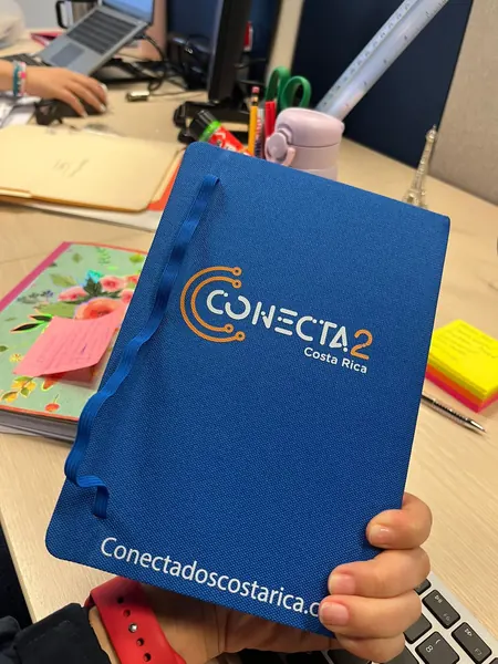 Libreta de tela azul con logotipo naranja y blanco y dirección web al pie
