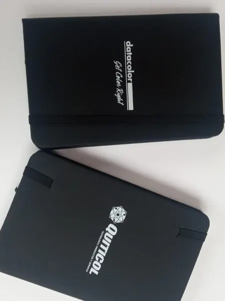 Dos libretas negras de tapa dura con logotipos impresos en blanco